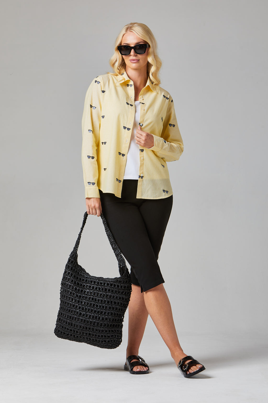 Buy Online Bella Shirt Alice Collins -  Woman wearing a yellow jacket with black patterns, holding a black bag on a gray background