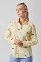 Woman wearing a light yellow shirt with small black and blue patterns on a plain background