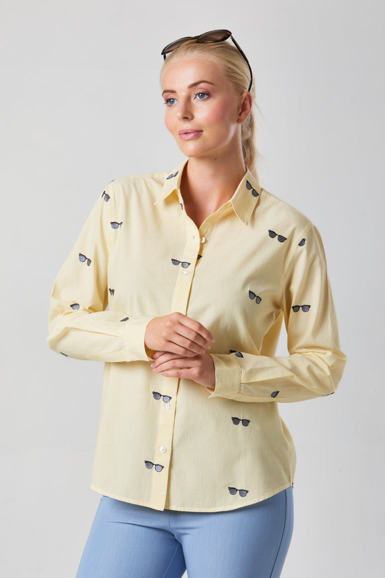 Buy Online Bella Shirt Alice Collins - Woman wearing a light yellow shirt with small dark patterns on a plain background