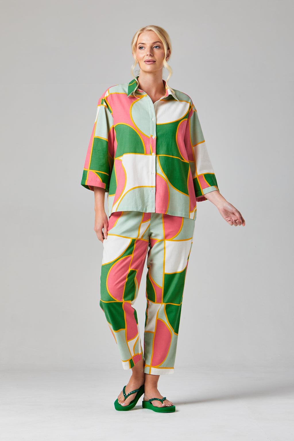 Buy Rosa Crop Trousers Online Alice Collins - Woman wearing a colorful outfit with a patterned shirt and pants on a gray background