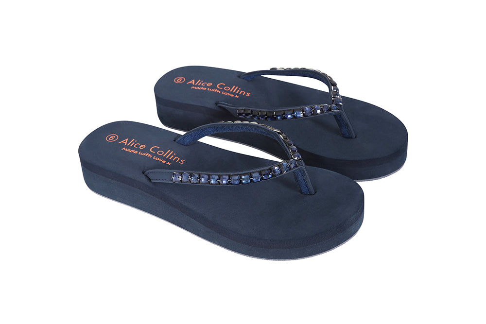 Pair of navy blue sandals with rhinestone straps on a white background