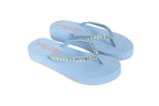 Pair of light blue flip-flops with decorative straps on a white background